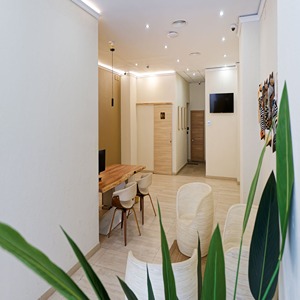 Sala moderna con sillas blancas, mesa de madera y plantas decorativas.