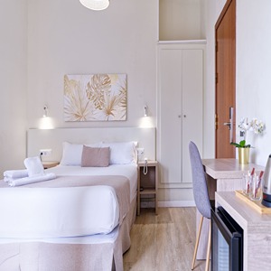 Habitaci&oacute;n de hotel moderna con cama doble, escritorio y decoraci&oacute;n minimalista.