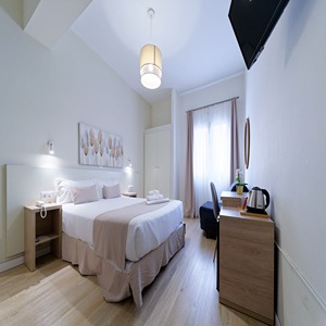 Habitaci&oacute;n de hotel luminosa con cama doble, escritorio y televisor.