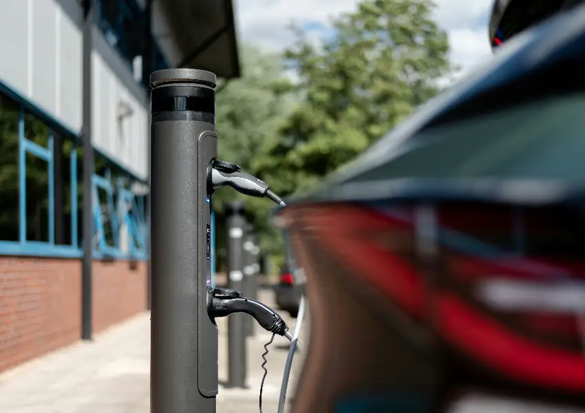 Coche el&eacute;ctrico cargando en una estaci&oacute;n al aire libre.
