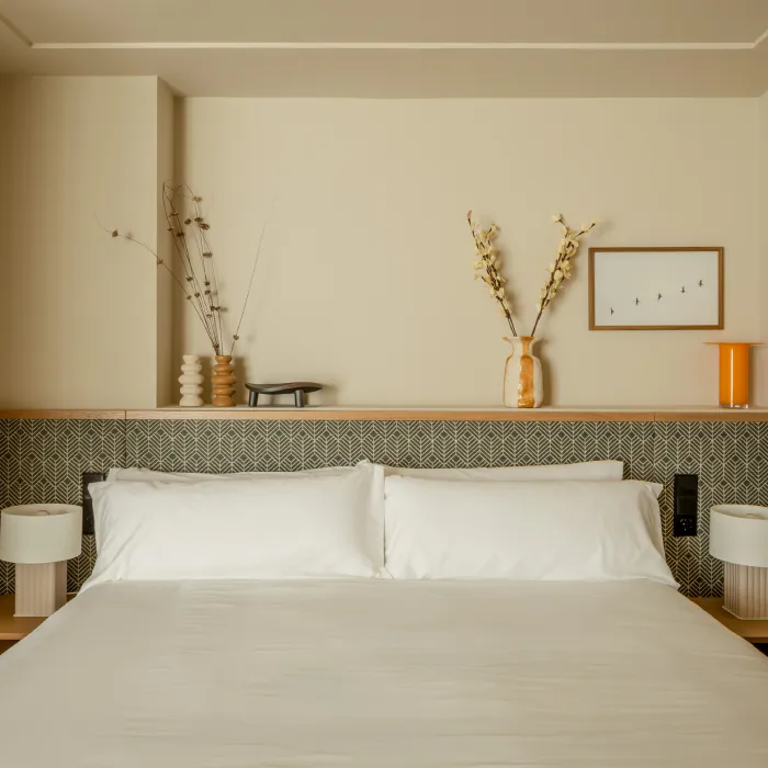 Cama matrimonial con decoraci&oacute;n minimalista y flores en jarrones.