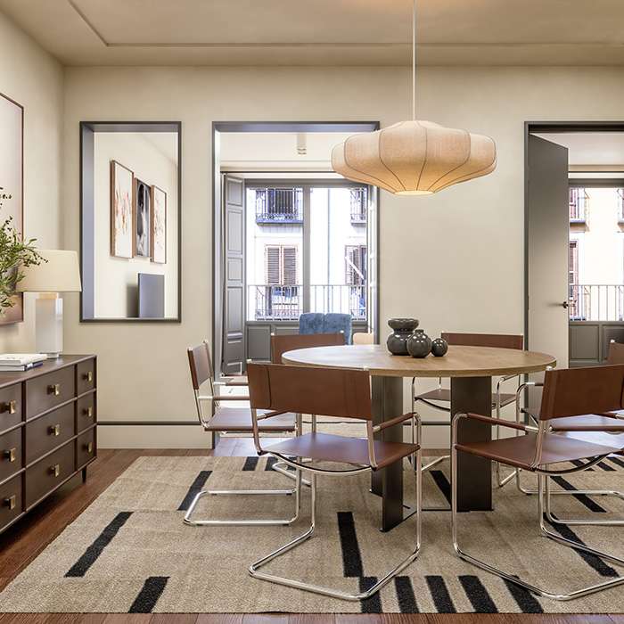 Comedor moderno con mesa redonda y l&aacute;mpara colgante, ventanas al fondo.