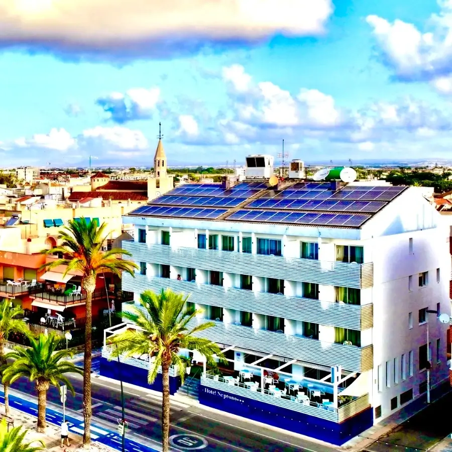 Hotel con paneles solares en el techo y piscina, vista aérea.