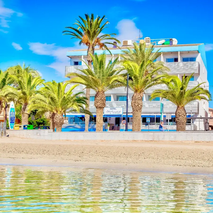 Hotel junto al mar con palmeras y cielo azul