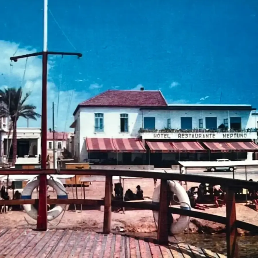Hotel Restaurante Neptuno junto al muelle y el mar, con toldos rojos