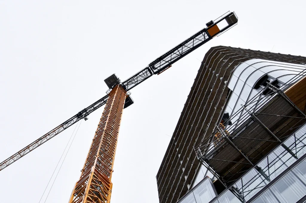 A yellow construction crane against a cloudy sky, highlighting modern architectural design
