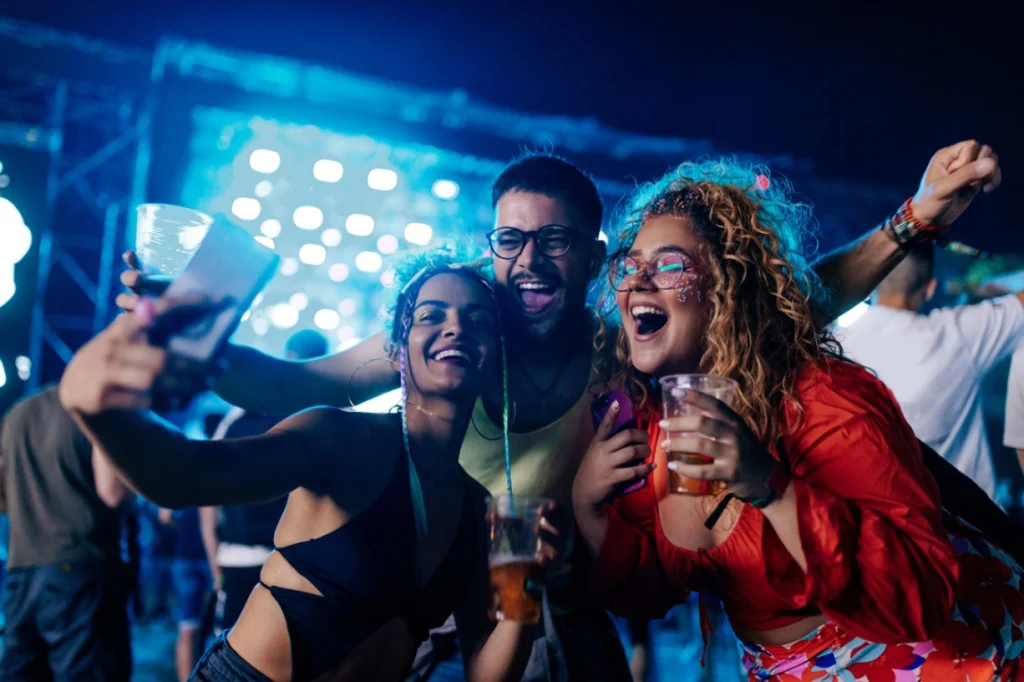 Group of friends enjoying a music festival, taking selfies and celebrating.