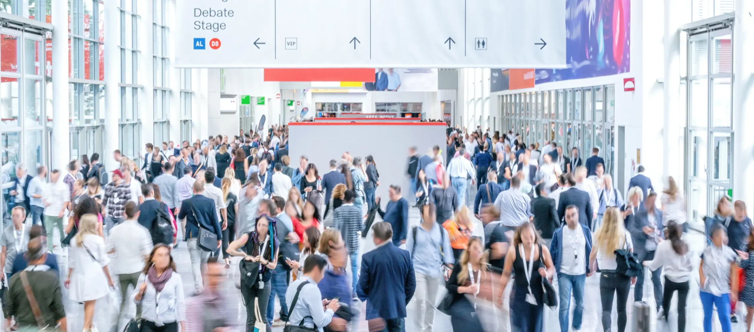 A bustling crowd at a conference with a debate stage in the background
