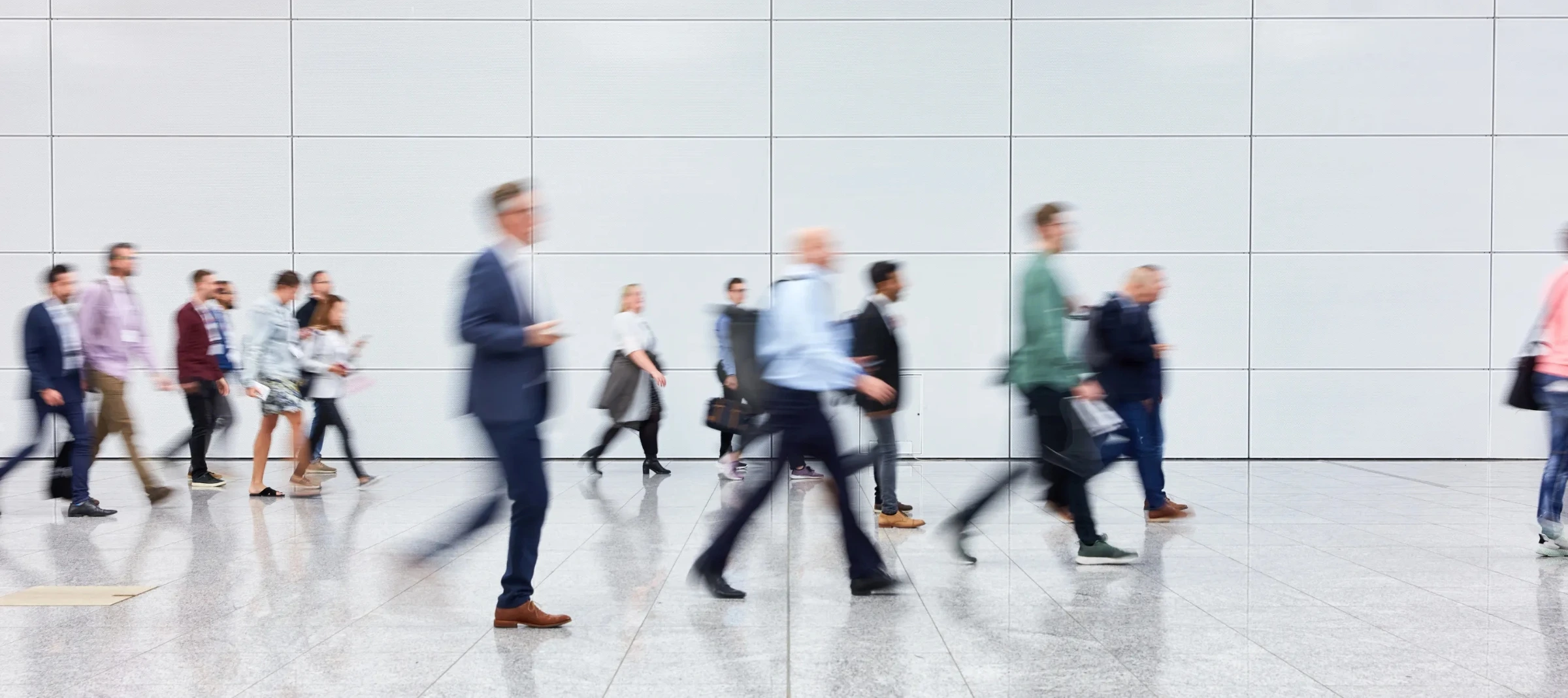 People walking in a modern office space with a sleek white wall