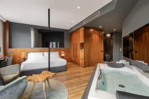 A modern room with a king-size bed, wooden closet, and a built-in jacuzzi tub