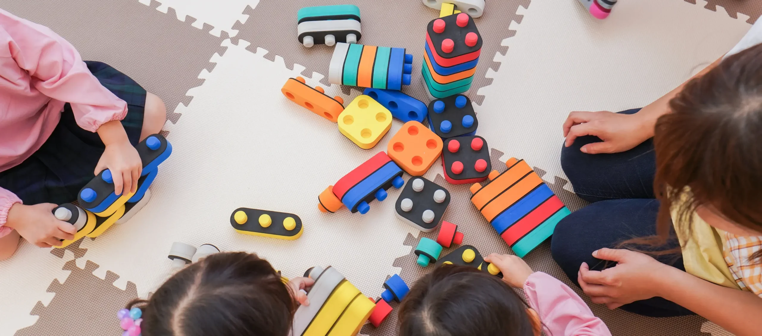 Children playing with colored blocks on a carpet.