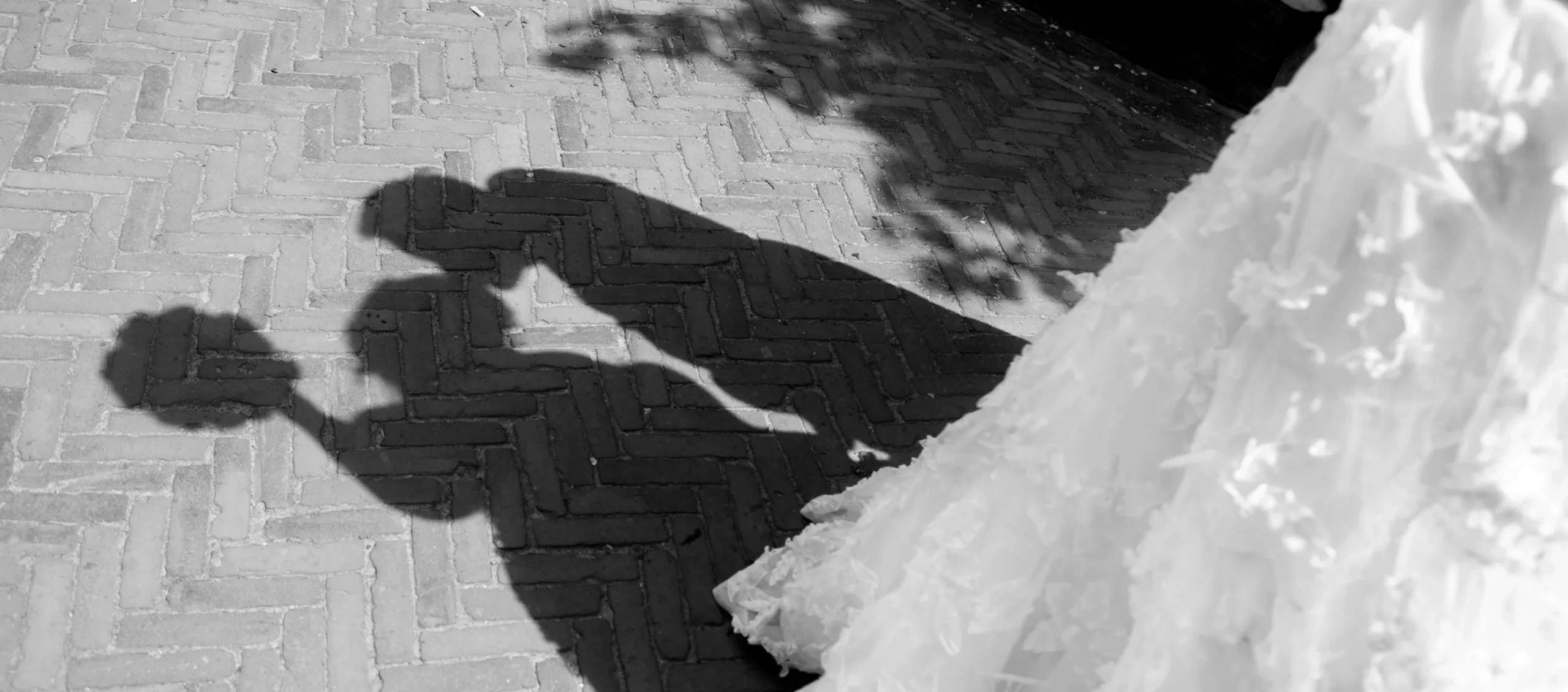 Shadows of a couple kissing on a brick path