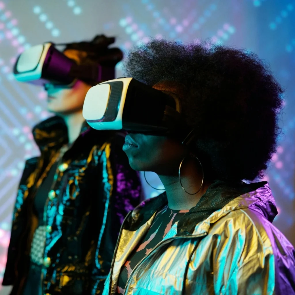 Two women wearing virtual reality goggles in a colorful environment.