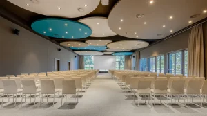 Spacious modern conference room with white chairs and blue ceiling accents.