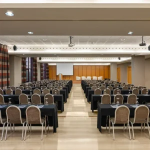 Modern meeting space featuring rows of tables and chairs with elegant decor.