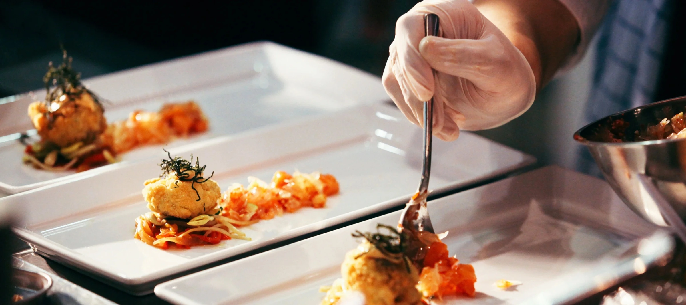 Close-up of a chef's hand delicately arranging food on a plate