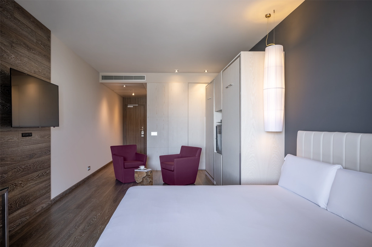 A stylish hotel room featuring a comfortable bed, modern decor, and cozy seating area.