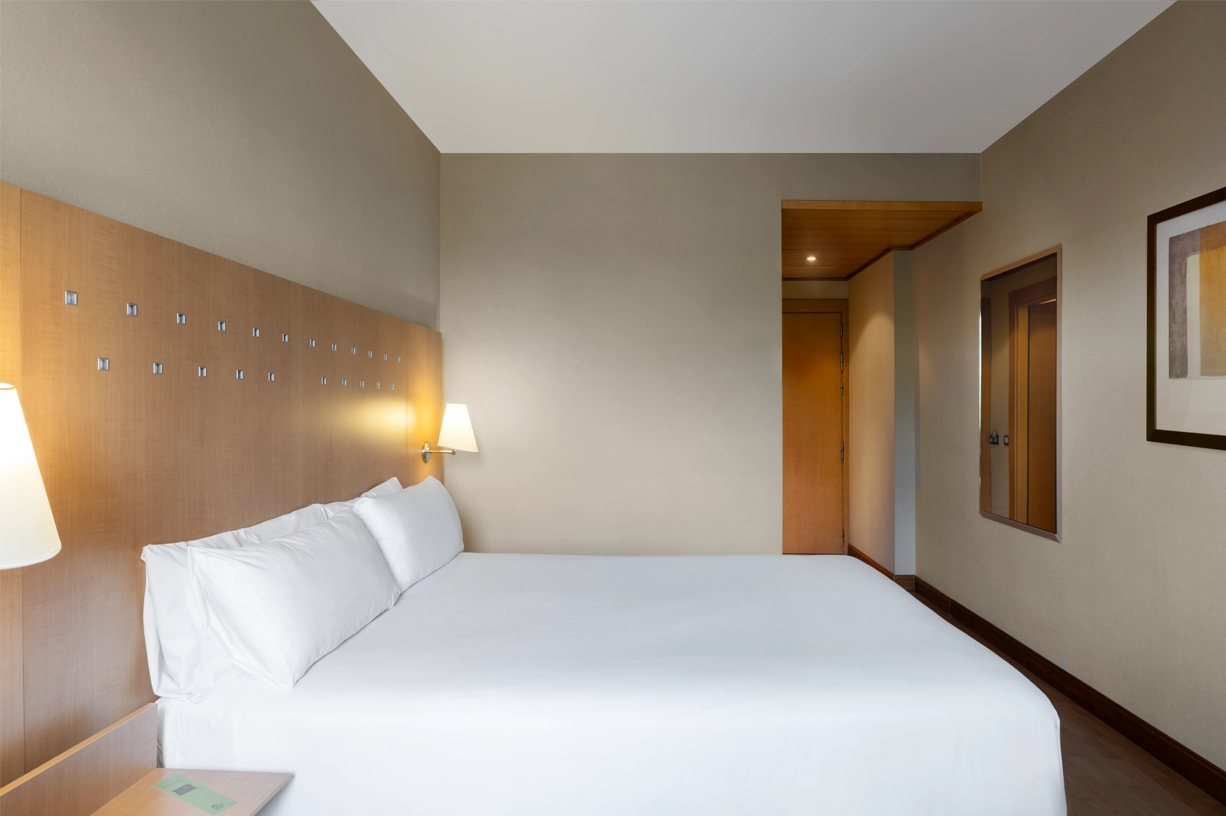 View of a modern bedroom with white bed and lamp