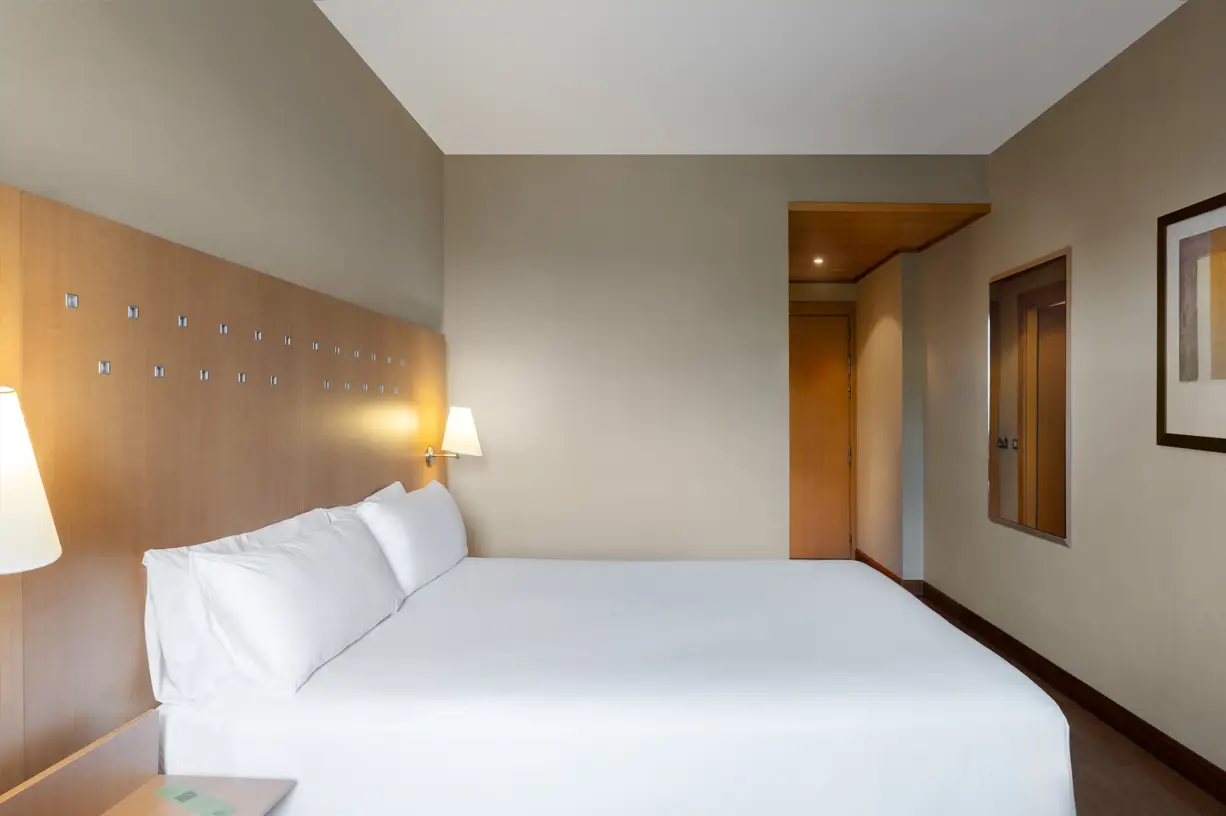 View of a modern bedroom with white bed and lamp