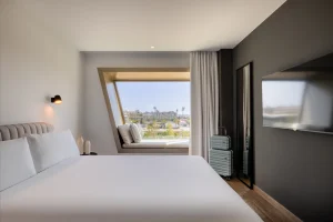Window with built-in and view of the cityscape in bedroom with double bed.
