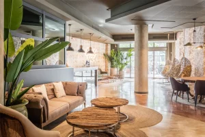 Una sala d'estar moderna i elegant amb un sofà acollidor, taules de cafè de fusta i plantes exuberants.