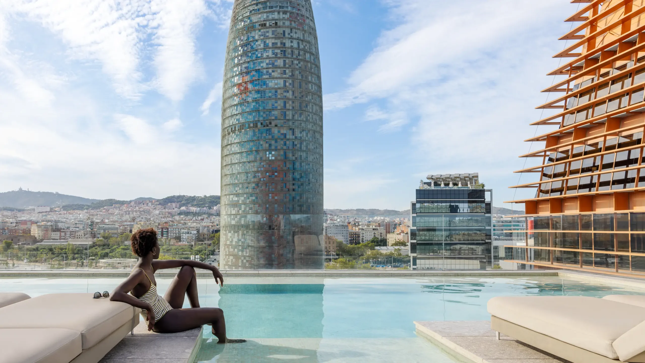 View of the swimming pool and the Agbar Tower on a sunny day in Barcelona.