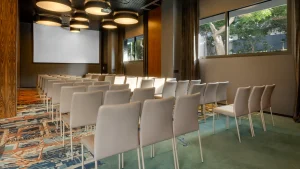 A modern conference room with a long, U-shaped table and a projection screen
