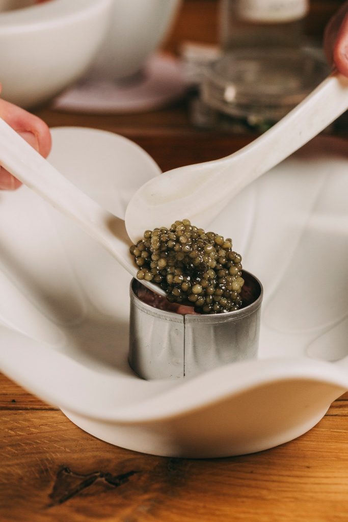 Caviar being served with porcelain spoons in a white dish.