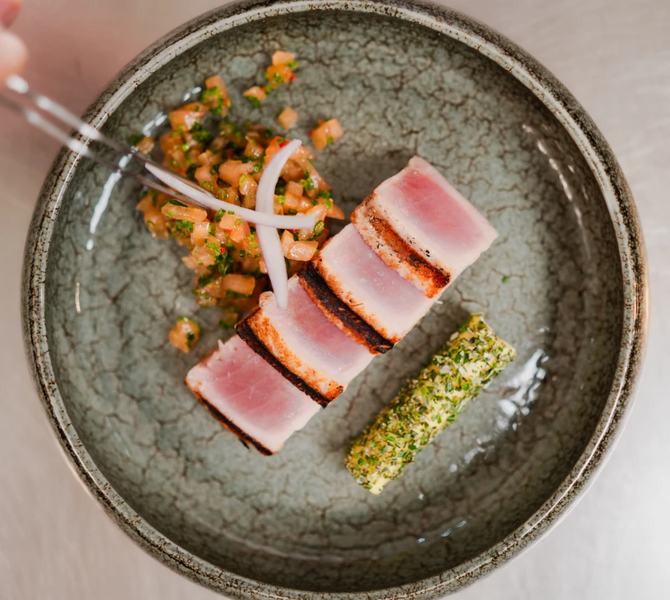 Plato con at&uacute;n sellado, guarnici&oacute;n y salsa en un cuenco.
