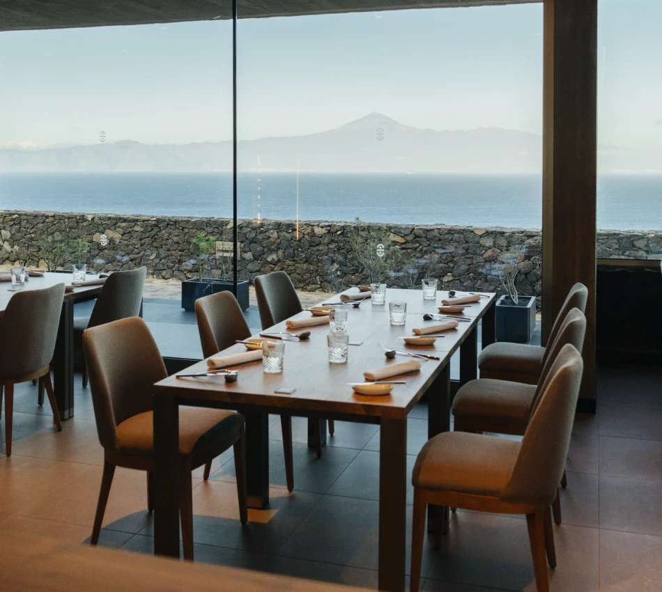 Restaurante moderno con vista al mar y monta&ntilde;as al fondo.