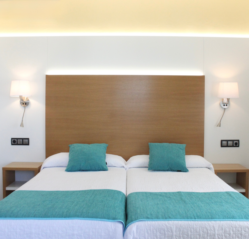 foto de habitacion doble con cabecero de madera con sabanas blancas y pleid y cojines de color