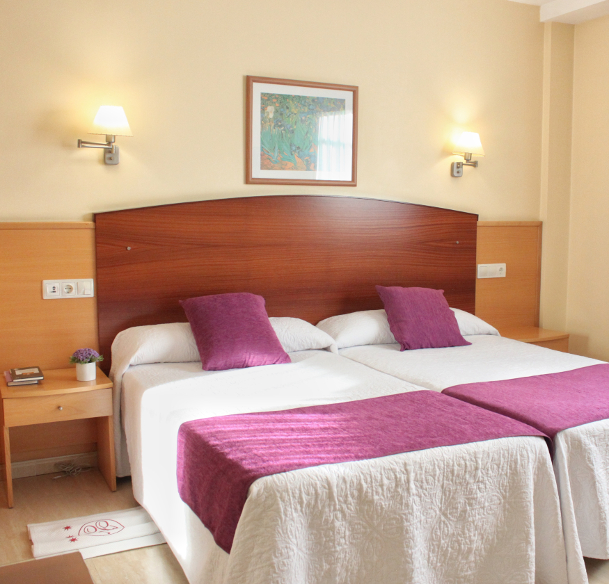 foto de habitacion doble con cabecero de madera con sabanas blancas y pleid y cojines de color