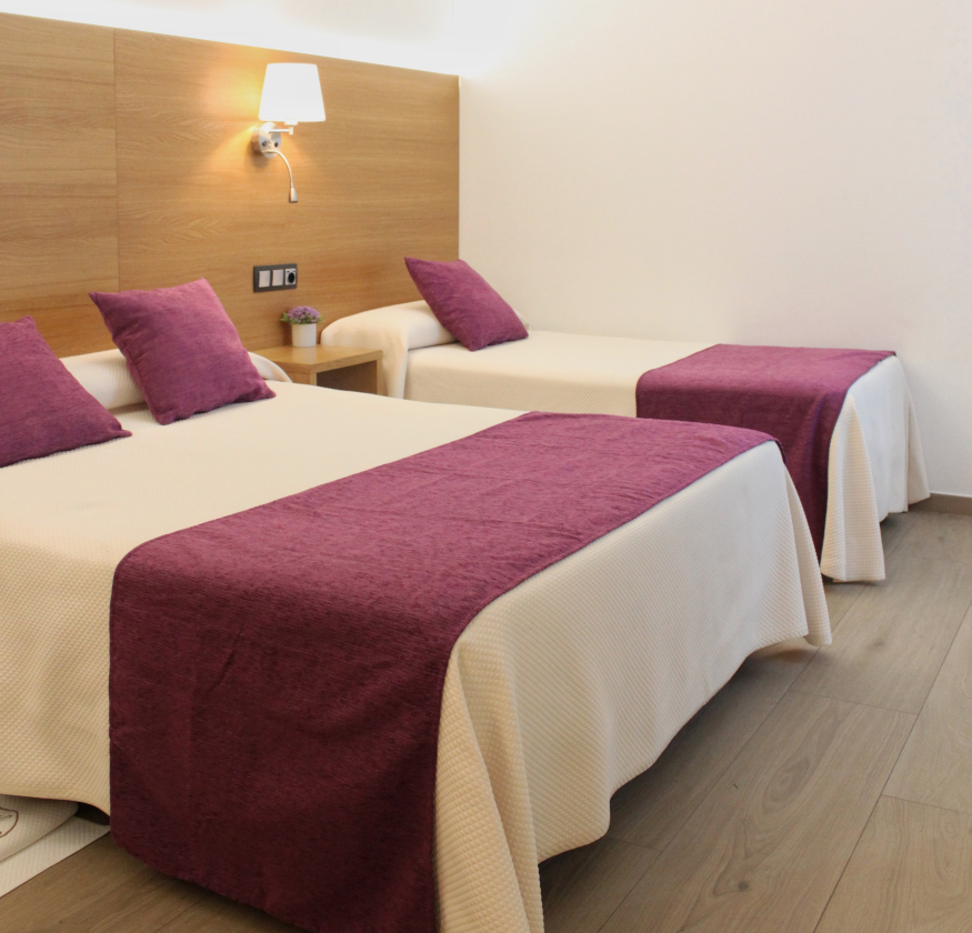 foto de habitacion doble con cabecero de madera con sabanas blancas y pleid y cojines de color