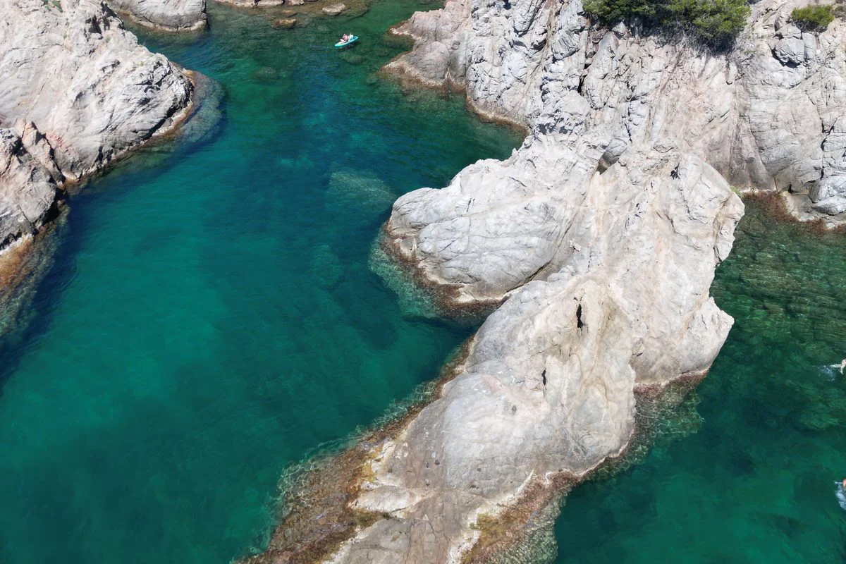 Rocas y agua clara junto a la costa de Lloret de Mar, ideal para kayak