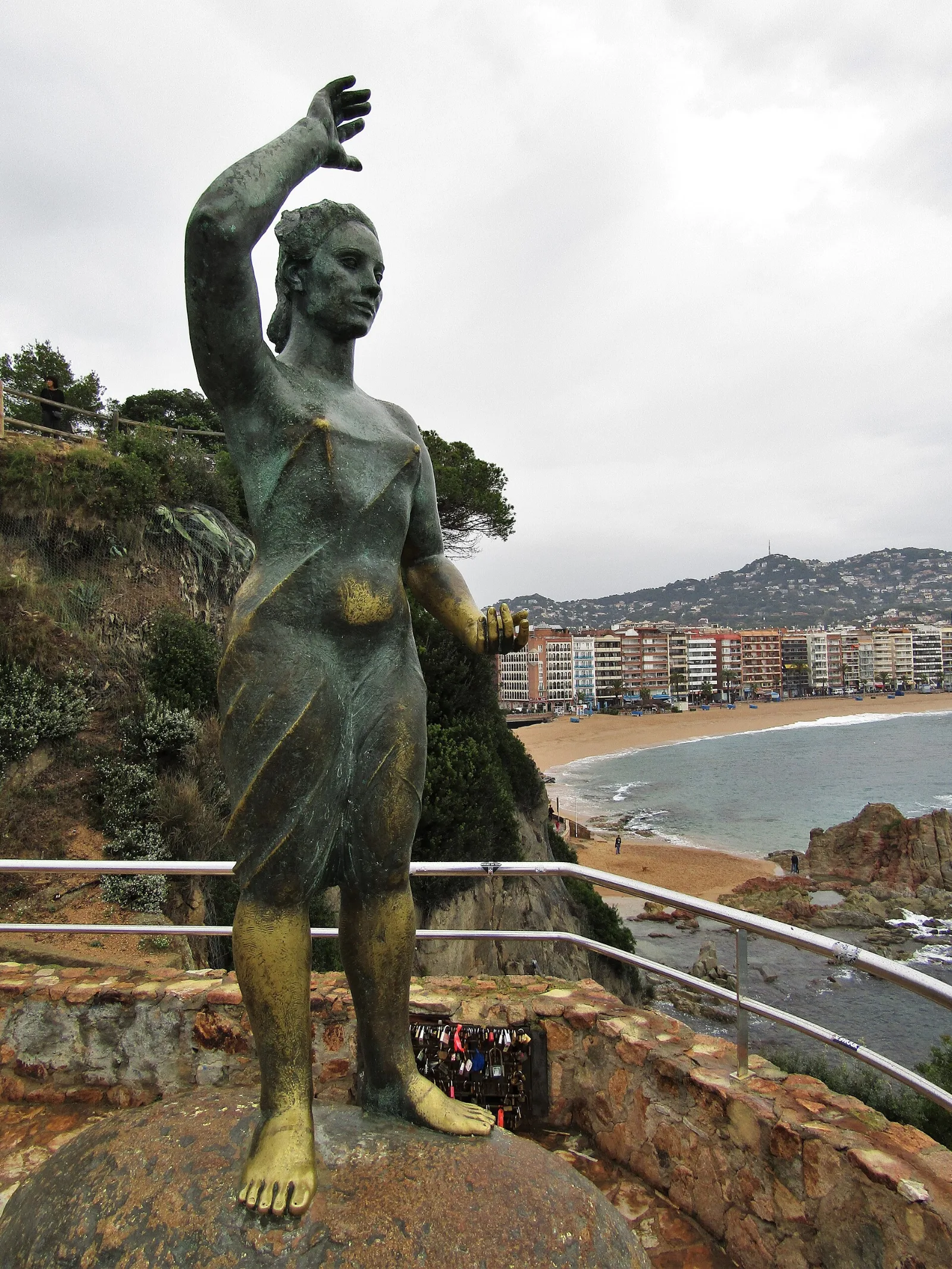 Estatua de bronce de la Dona Marinera mirando al mar sobre la playa de Lloret