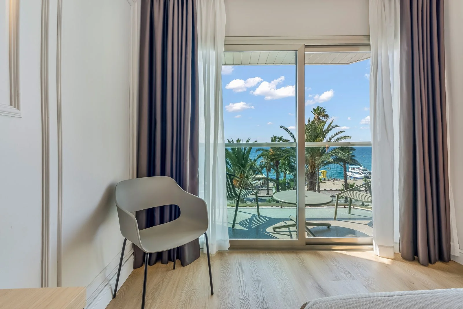 Habitación con terraza y vistas al mar entre palmeras en el Hotel Miramar de Lloret