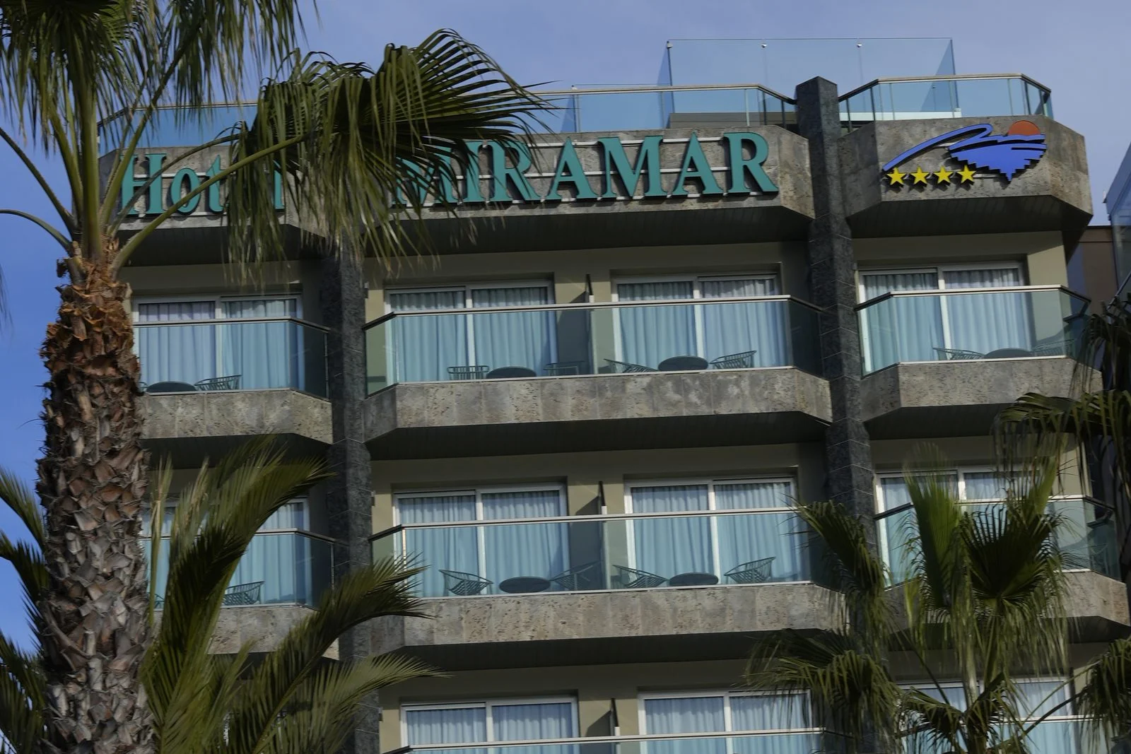 Fachada del Hotel Miramar con palmeras y cielo azul en verano