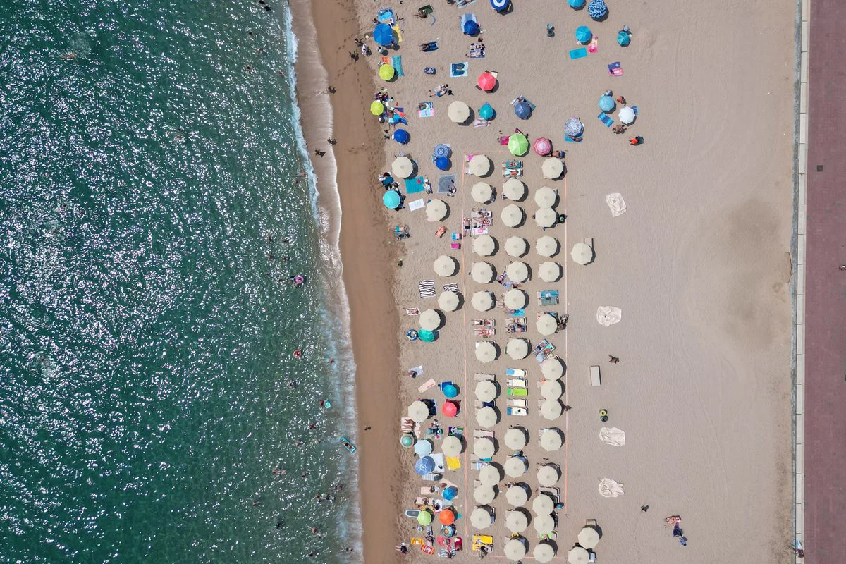 Vista a&eacute;rea de la playa de Lloret de Mar con familias y sombrillas