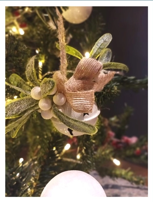 Enfeite de Natal em árvore com laço e folhas ornamentais.