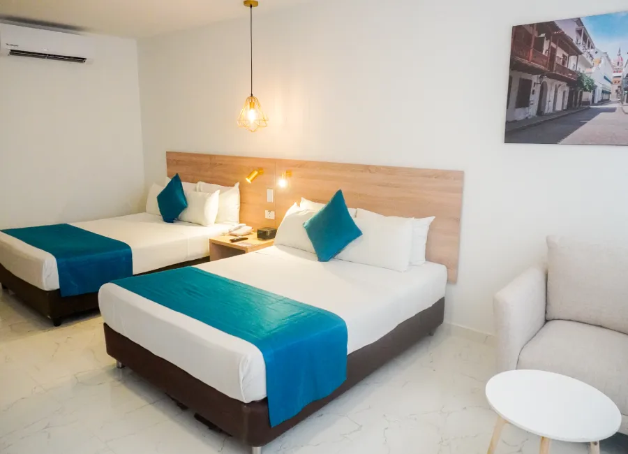 Dormitorio moderno con cama doble, cojines azules y sofá blanco.