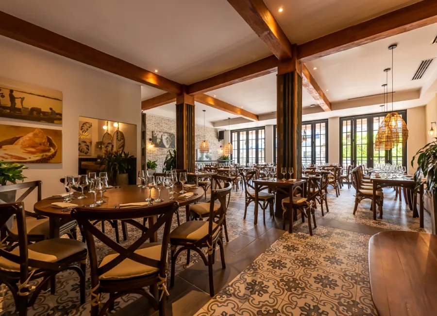 Comedor rústico con mesas, sillas y lámparas colgantes en espacio luminoso