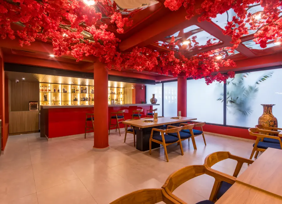 Bar moderno con luces, sillas de madera y &aacute;rboles rojos decorativos en el techo