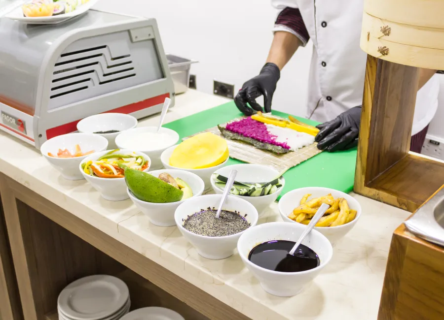 Chef prepara comida en estación con verduras, sal, salsas y olla de cocción
