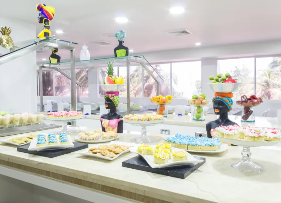 Buffet de postres con figuras decorativas y bandejas en mesa blanca.