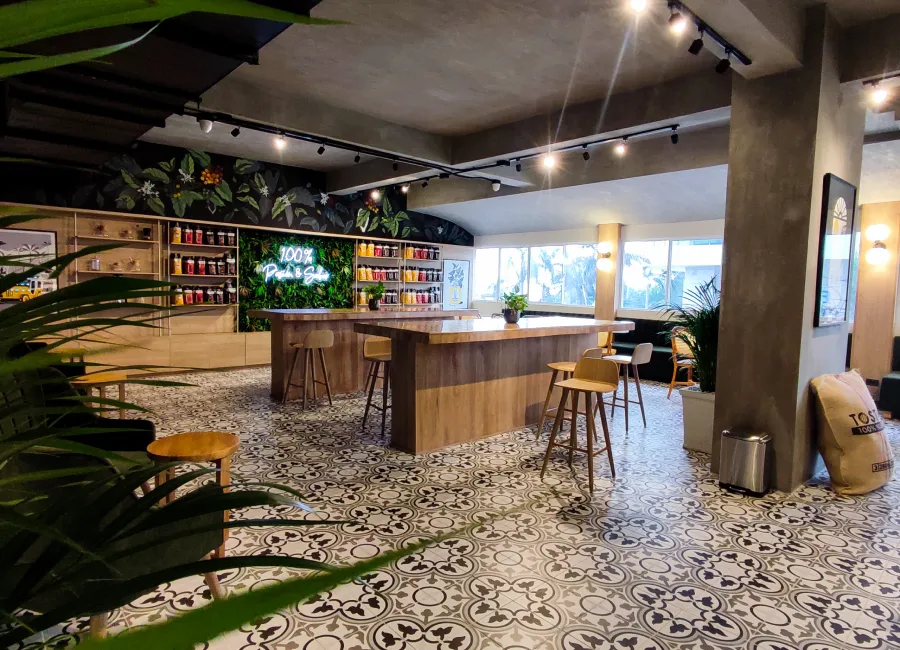 Interior de bar moderno con barra de madera, mesas y luces colgantes