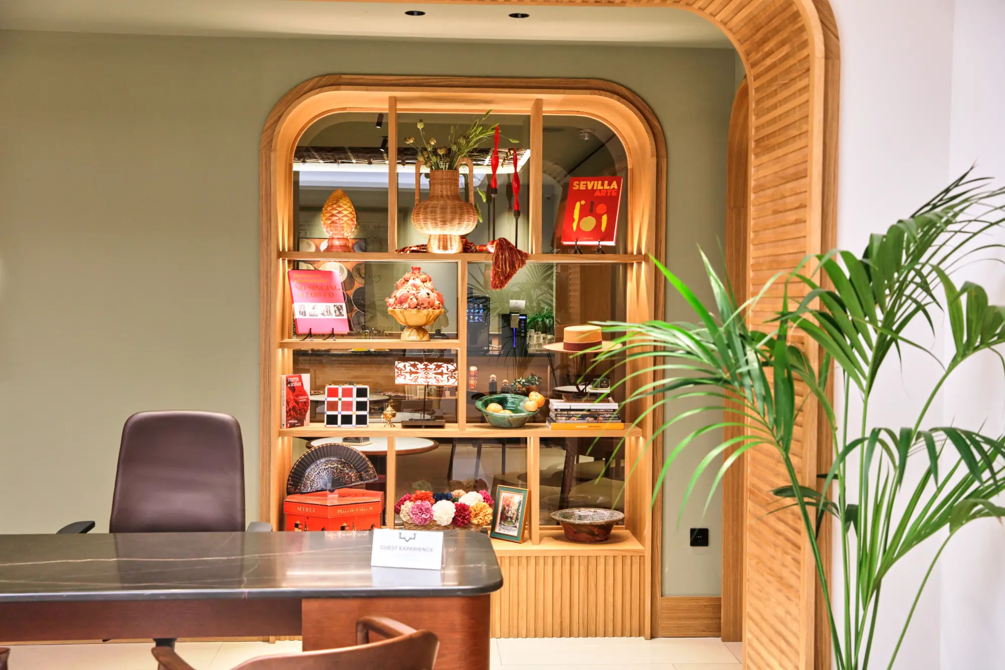 Oficina con estante decorativo de artículos coloridos, junto a una planta interior.