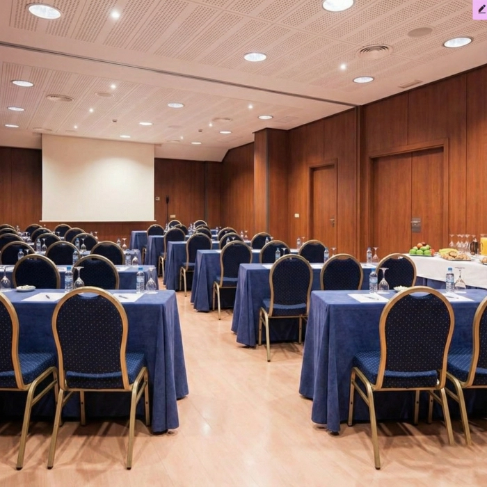 Sala de conferencias con sillas y mesas azules, lista para un evento.