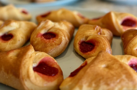 Empanadillas doradas con relleno rojo, sobre bandeja blanca.