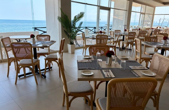 Restaurante junto al mar con mesas, sillas y vista al oc&eacute;ano.
