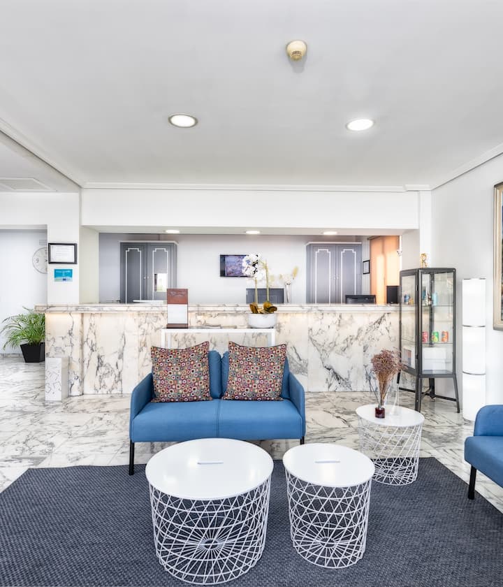 Vestíbulo moderno con muebles azules, mesitas blancas y mostrador de mármol. Decoración elegante.
